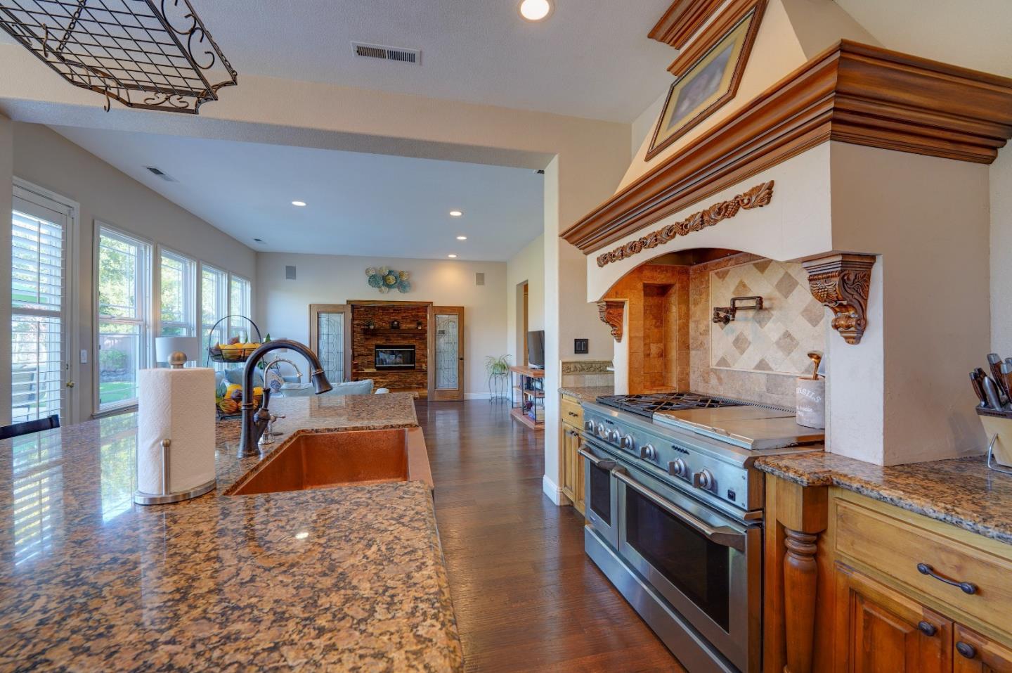 2400 Club Drive Gilroy, CA 95020 - Photo 18 of 67 a kitchen with stainless steel appliances granite countertop a stove top oven a sink a dining table and chairs with wooden floor
