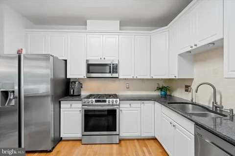 a kitchen with granite countertop white cabinets stainless steel appliances and sink