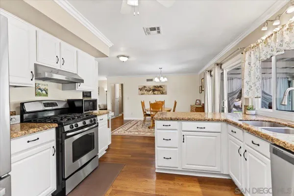 a kitchen with granite countertop a sink stainless steel appliances and white cabinets