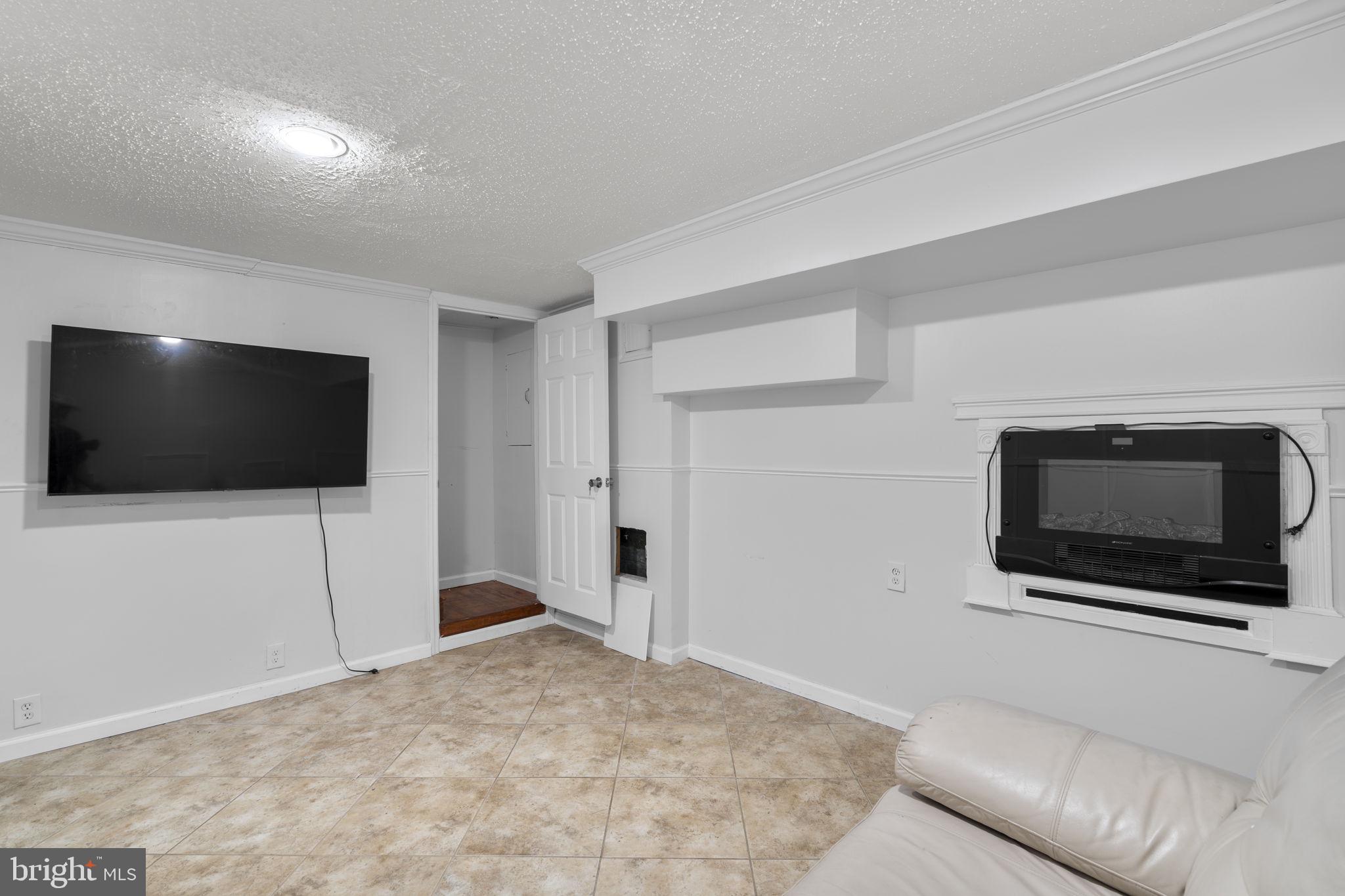 1232 Savannah Place Southeast Washington, DC 20032 - Photo 22 of 29 a living room with a flat screen tv a rug and a white door