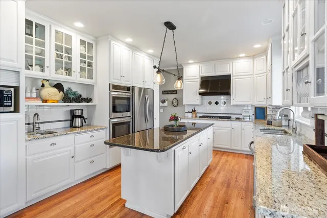 a large kitchen with stainless steel appliances kitchen island granite countertop a sink stove and refrigerator