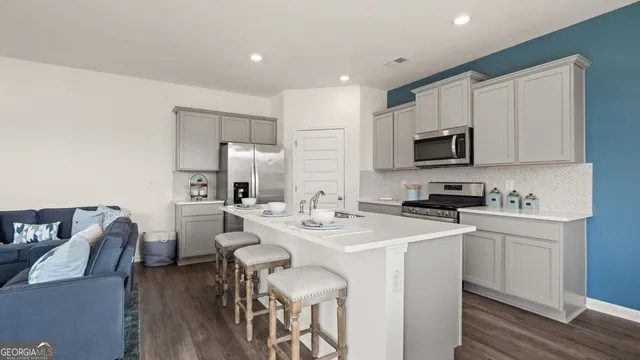 a kitchen with stainless steel appliances a stove a sink a microwave a refrigerator a stove a dining table and chairs