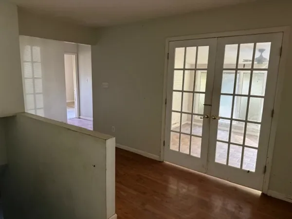 an empty room with wooden floor and windows