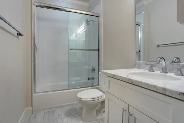a bathroom with a granite countertop sink a toilet and shower