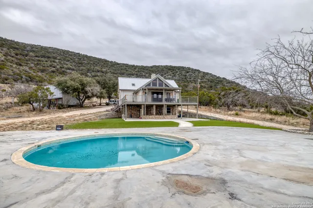 a view of a swimming pool with a yard and large trees