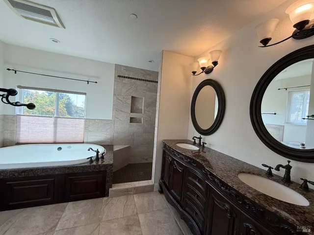 a bathroom with a bathtub double vanity sink and a mirror