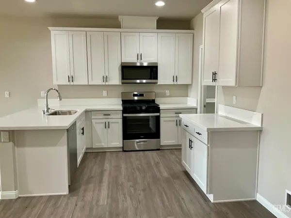 a kitchen with stainless steel appliances granite countertop a stove top oven a sink and white cabinets