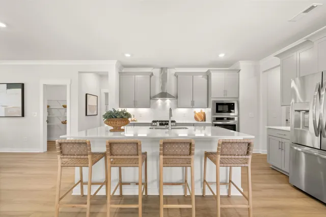 a kitchen with stainless steel appliances granite countertop a stove top oven a sink a dining table and chairs with wooden floor