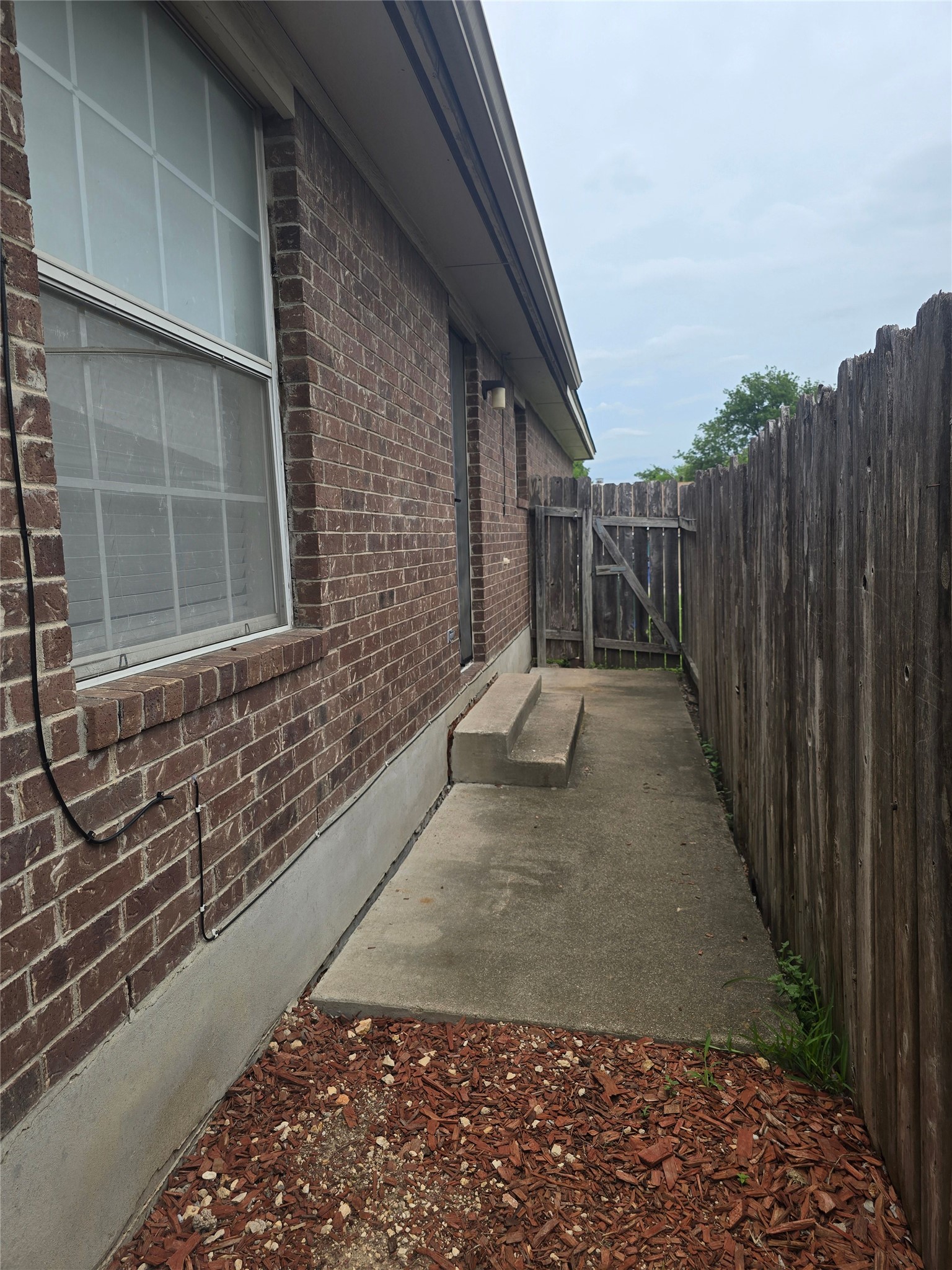 2005 Alex Avenue Austin, TX 78728 - Photo 10 of 12 A well-maintained brick exterior with a privacy fence creating a secluded pathway.
