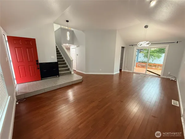 an empty room with wooden floor fireplace and windows