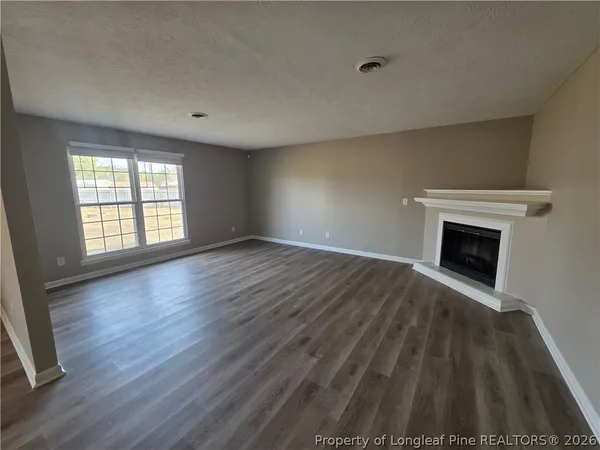 a view of empty room with wooden floor and fireplace