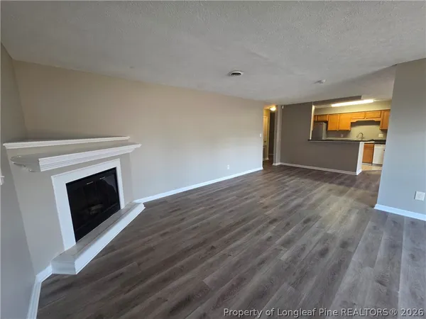 a view of a livingroom with wooden floor and a fireplace