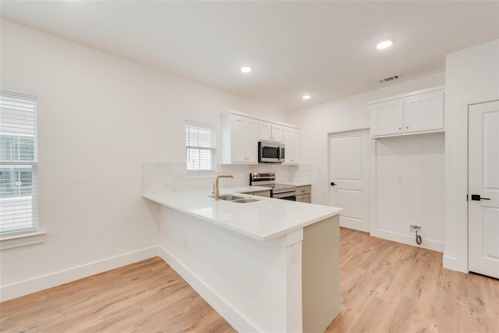 1807 Franklin Street Bonham, TX 75418 - Photo 4 of 13 a kitchen with a sink a stove a refrigerator and white cabinets with wooden floor