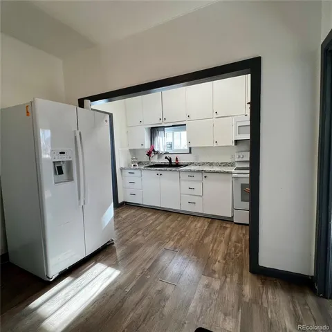 a kitchen with granite countertop a refrigerator stove top oven and sink