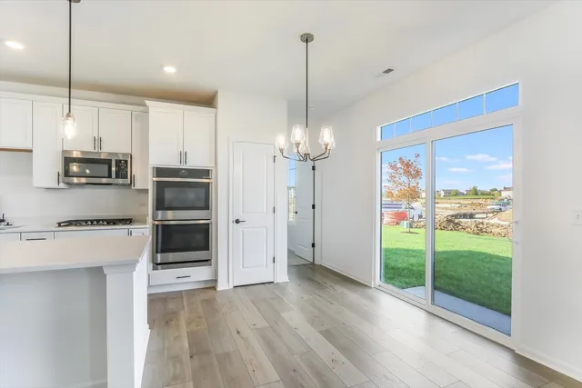 a kitchen with stainless steel appliances kitchen island granite countertop a refrigerator a stove and a wooden floor