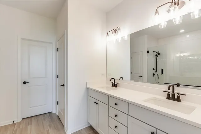 a bathroom with a double vanity sink a mirror and shower