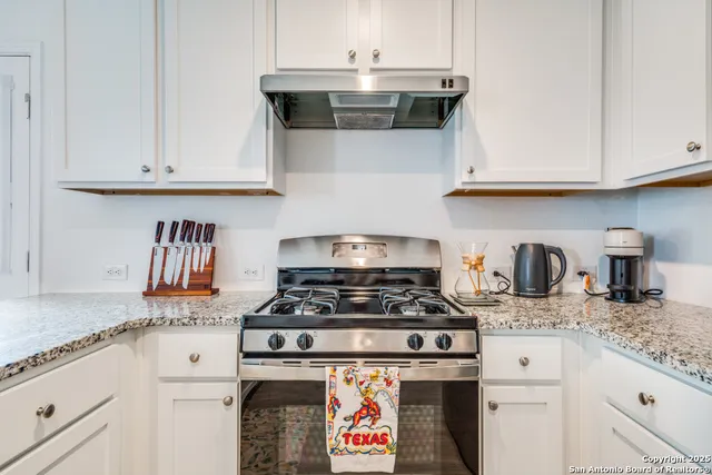 a kitchen with granite countertop white cabinets and stainless steel appliances