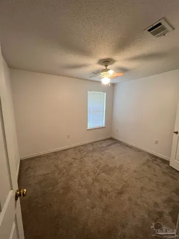 an empty room with a ceiling fan and window