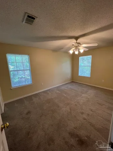 en empty room with windows and chandelier fan