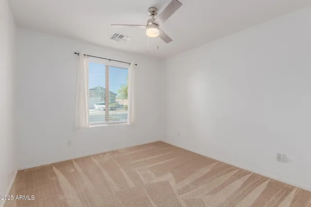 an empty room with a window and ceiling fan