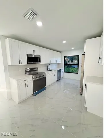 a kitchen with white cabinets and white appliances