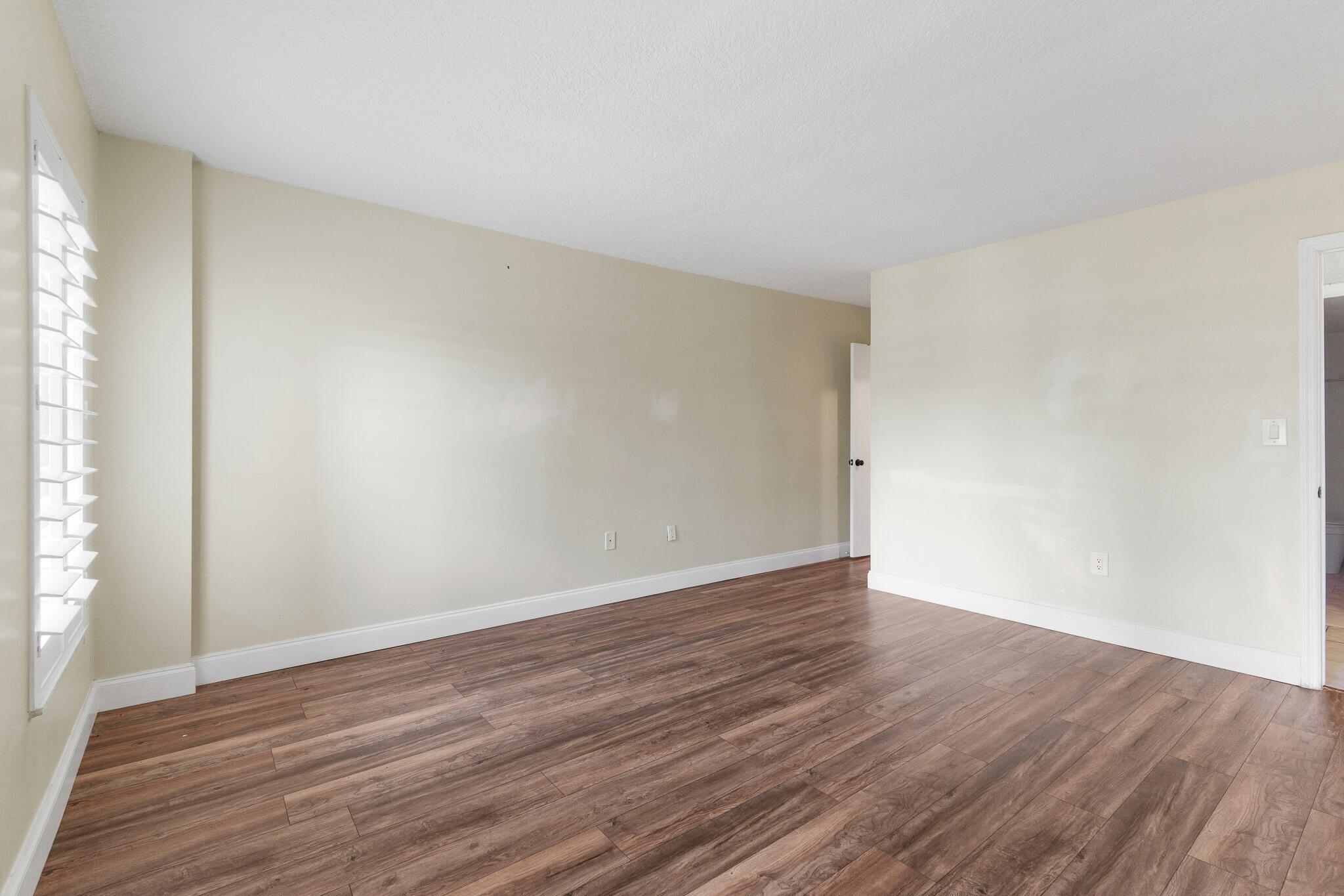 951 De Soto Road, Unit 130 Boca Raton, FL 33432 - Photo 12 of 38 a view of an empty room with wooden floor and a window