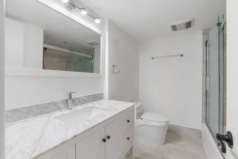 a bathroom with a granite countertop sink a toilet and a mirror