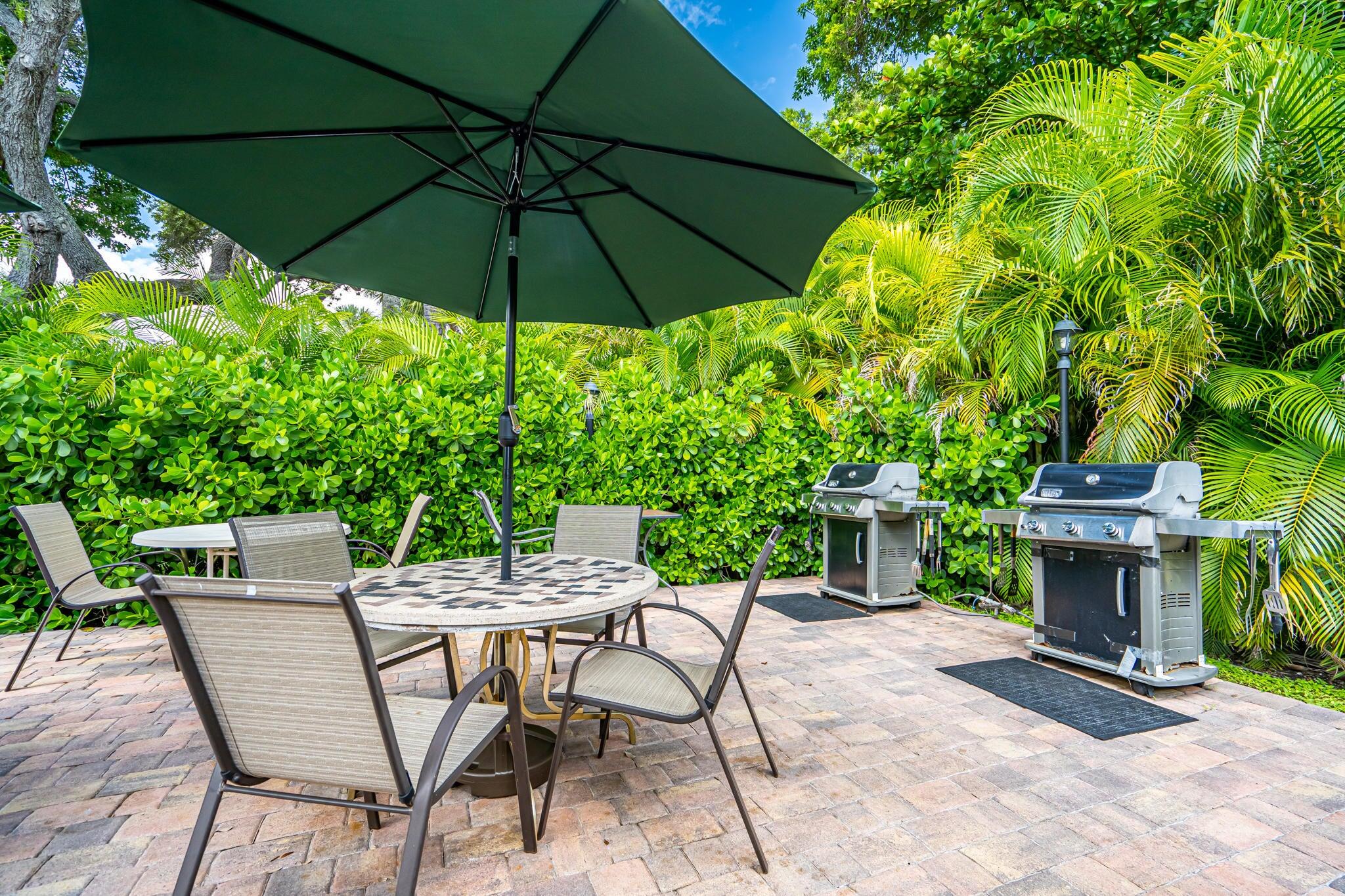 951 De Soto Road, Unit 130 Boca Raton, FL 33432 - Photo 28 of 38 a view of an chairs and table under an umbrella