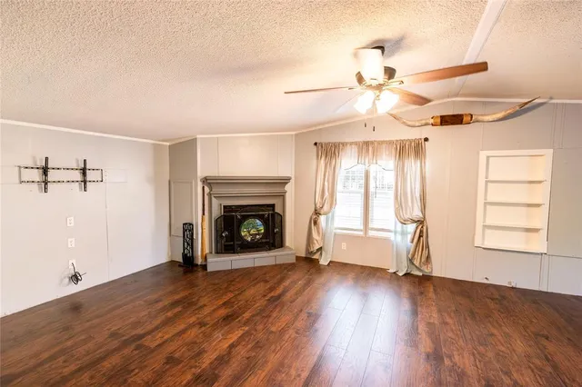 an empty room with wooden floor fireplace and windows