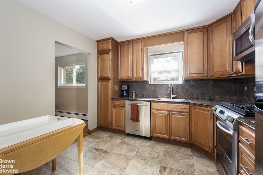 5834 Fieldston Road Bronx, NY 10471 - Photo 6 of 15 a kitchen with stainless steel appliances granite countertop a stove a sink and a microwave