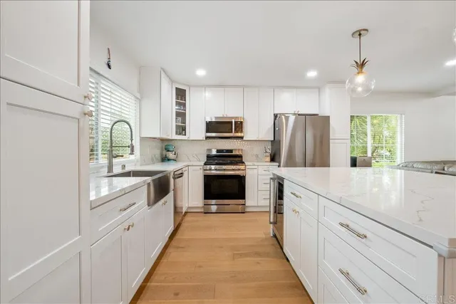 a kitchen with kitchen island granite countertop stainless steel appliances cabinets a sink and a large window