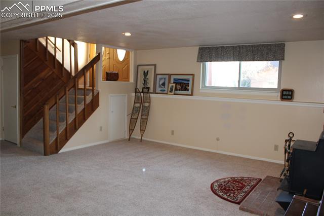 8340 Piute Road Colorado Springs, CO 80926 - Photo 37 of 48 Family room with a wood stove, carpet, stairway, and recessed lighting
