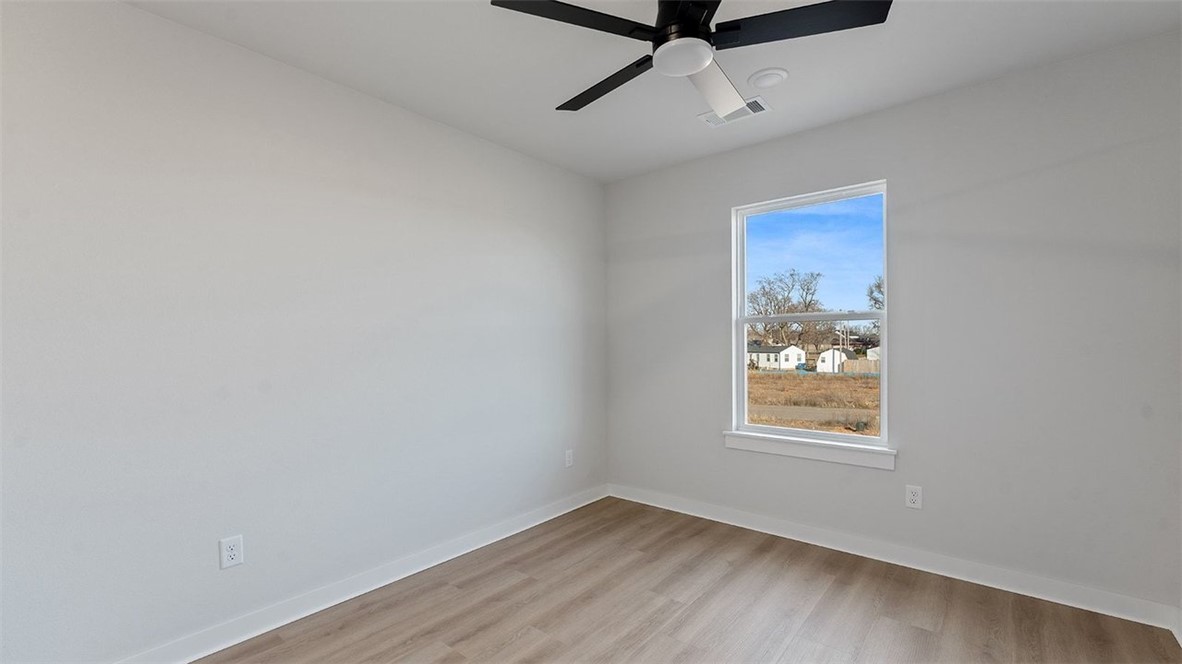 1715 Cuppett Circle Pea Ridge, AR 72751 - Photo 9 of 15 Light-filled room featuring a single window, wood-finish flooring, a contemporary ceiling fan, white baseboards, and neutral wall paint