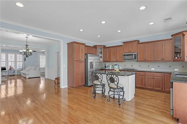 a kitchen with stainless steel appliances granite countertop a refrigerator a stove top oven and a dining table with wooden floor