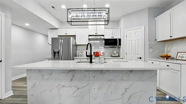 a kitchen with stainless steel appliances granite countertop a sink and a refrigerator