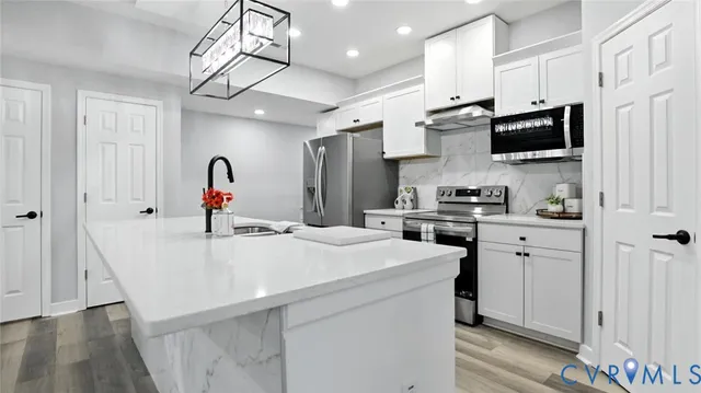 a kitchen with stainless steel appliances kitchen island a white cabinets and refrigerator