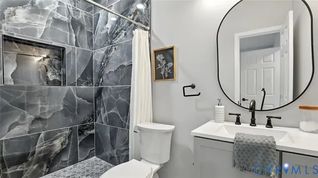 a bathroom with a granite countertop toilet sink and mirror