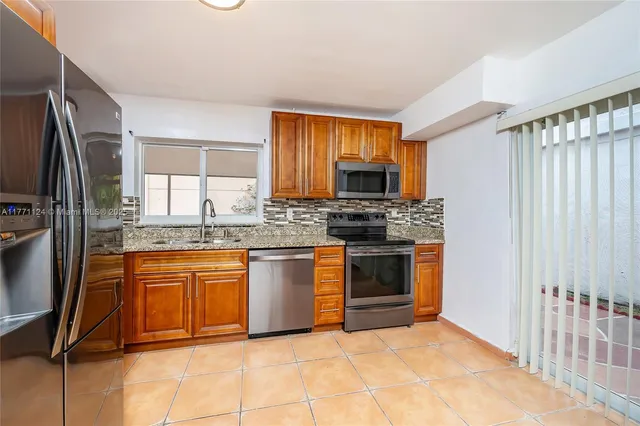 a kitchen with stainless steel appliances granite countertop a refrigerator and a stove top oven