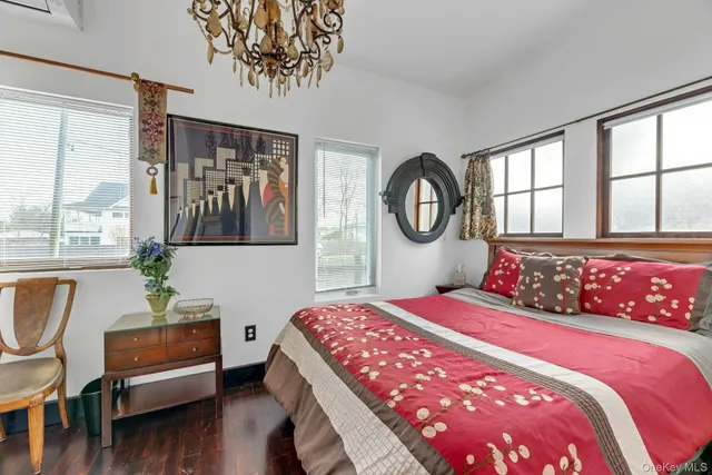 a bedroom with a bed a dresser and a large window