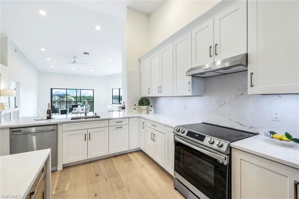 a kitchen with stainless steel appliances granite countertop a stove and white cabinets