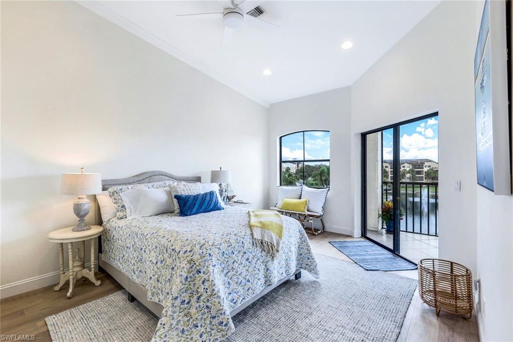 195 Vintage Circle, Unit E403 Naples, FL 34119 - Photo 19 of 39 a bedroom with a large bed and a chandelier fan