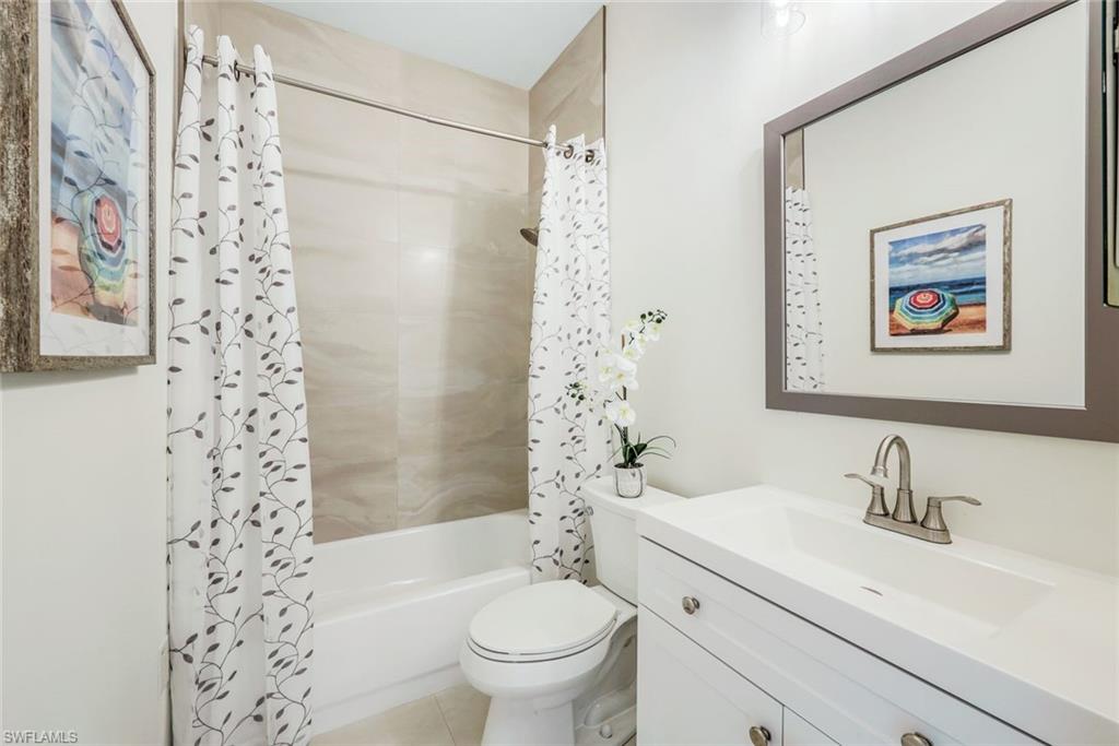 195 Vintage Circle, Unit E403 Naples, FL 34119 - Photo 24 of 39 a bathroom with a sink a toilet and shower curtain