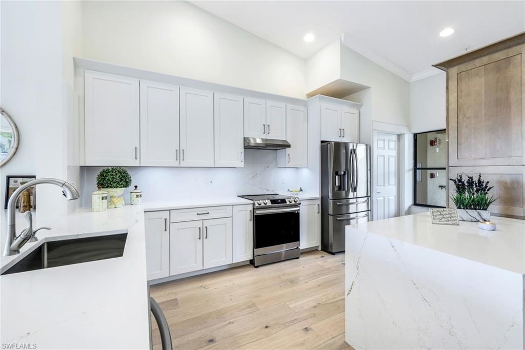 195 Vintage Circle, Unit E403 Naples, FL 34119 - Photo 3 of 39 a kitchen with stainless steel appliances kitchen island granite countertop a refrigerator sink and white cabinets