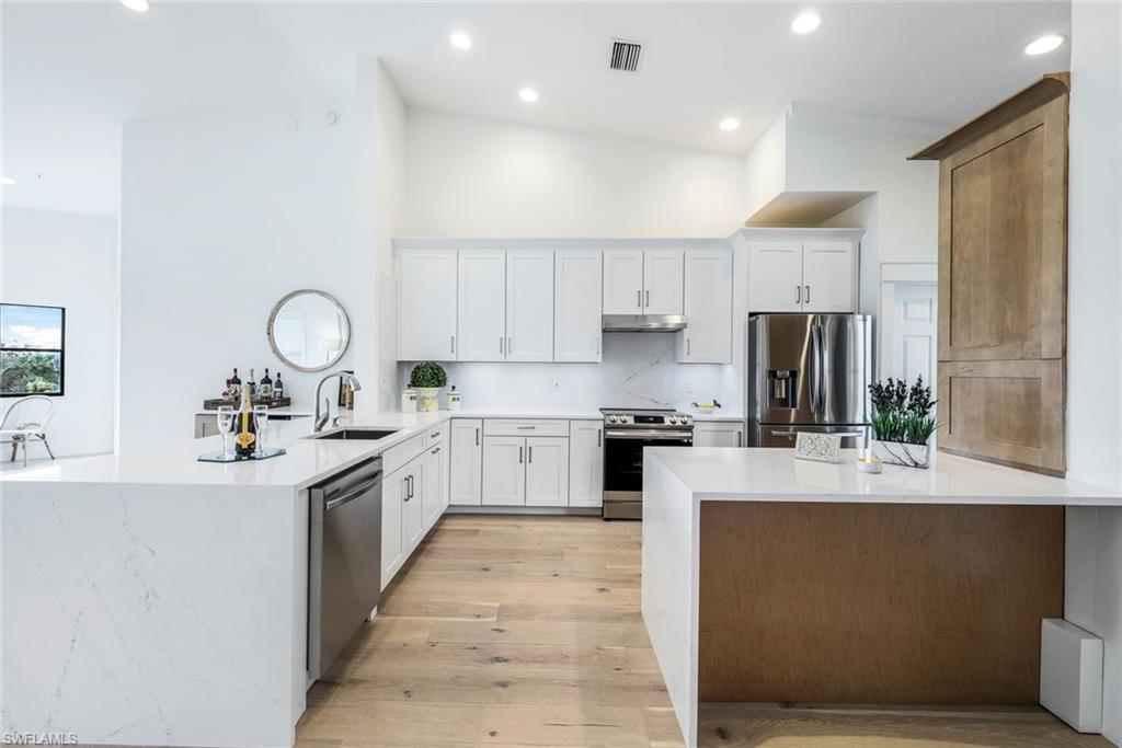 195 Vintage Circle, Unit E403 Naples, FL 34119 - Photo 4 of 39 a large kitchen with stainless steel appliances lots of counter space and wooden floor