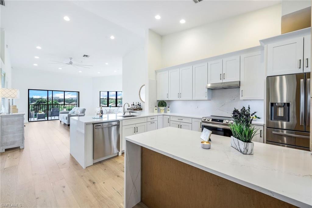 195 Vintage Circle, Unit E403 Naples, FL 34119 - Photo 9 of 39 a kitchen with white cabinets and stainless steel appliances