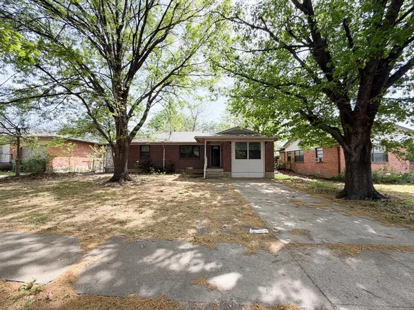 a front view of a house with a garden and trees