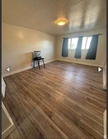 106 East Richelman Lane Wellington, UT 84542 - Photo 16 of 35 Unfurnished room with dark wood finished floors and a textured ceiling
