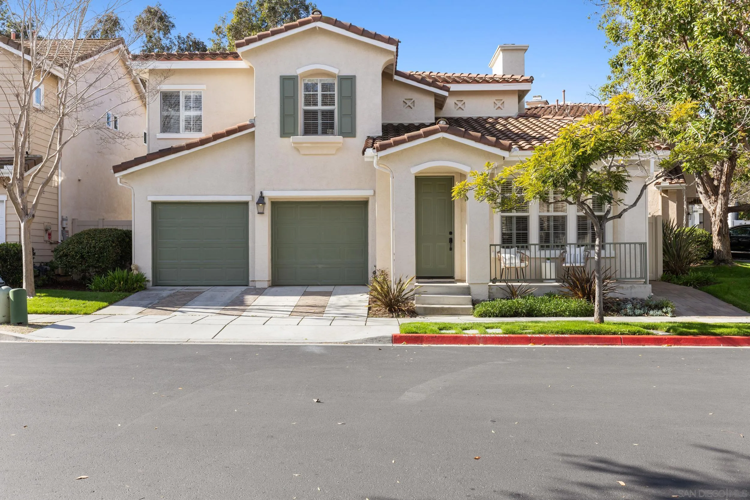 a view of a white house with a small yard and large trees