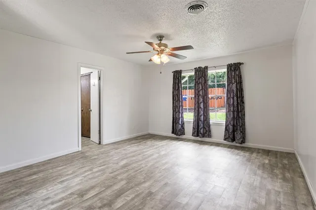an empty room with windows and ceiling fan
