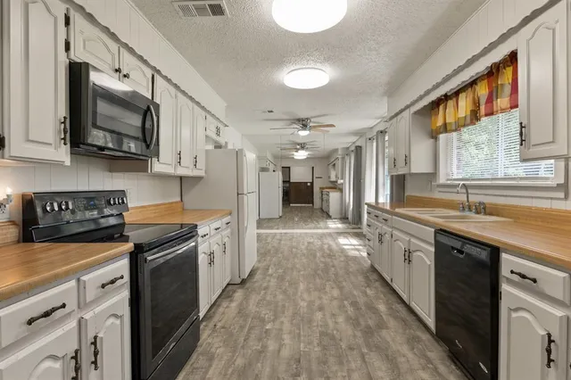 a kitchen with stainless steel appliances granite countertop a sink a stove top oven a refrigerator with white cabinets and black appliances